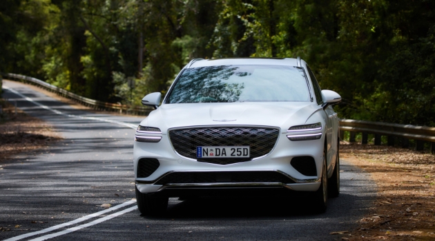 A white GV70 Advanced driving on the road
