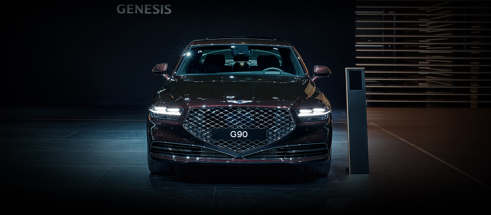 Genesis G90 burgundy  front profile in showroom 