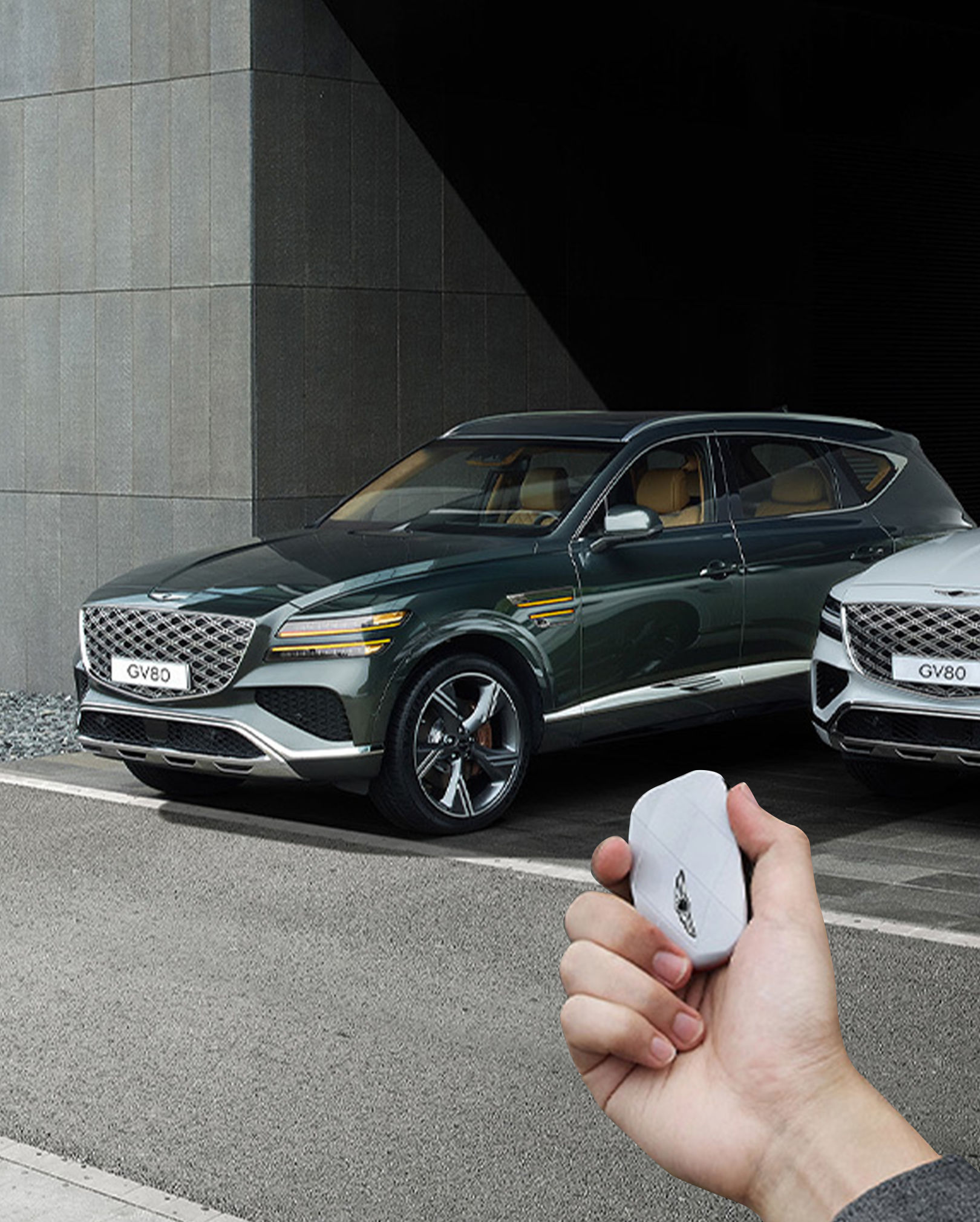 A Vik Black GV80 Coupe and a Uyuni White GV80 Coupe are parked, and the driver is operating the smart key outside the vehicle.