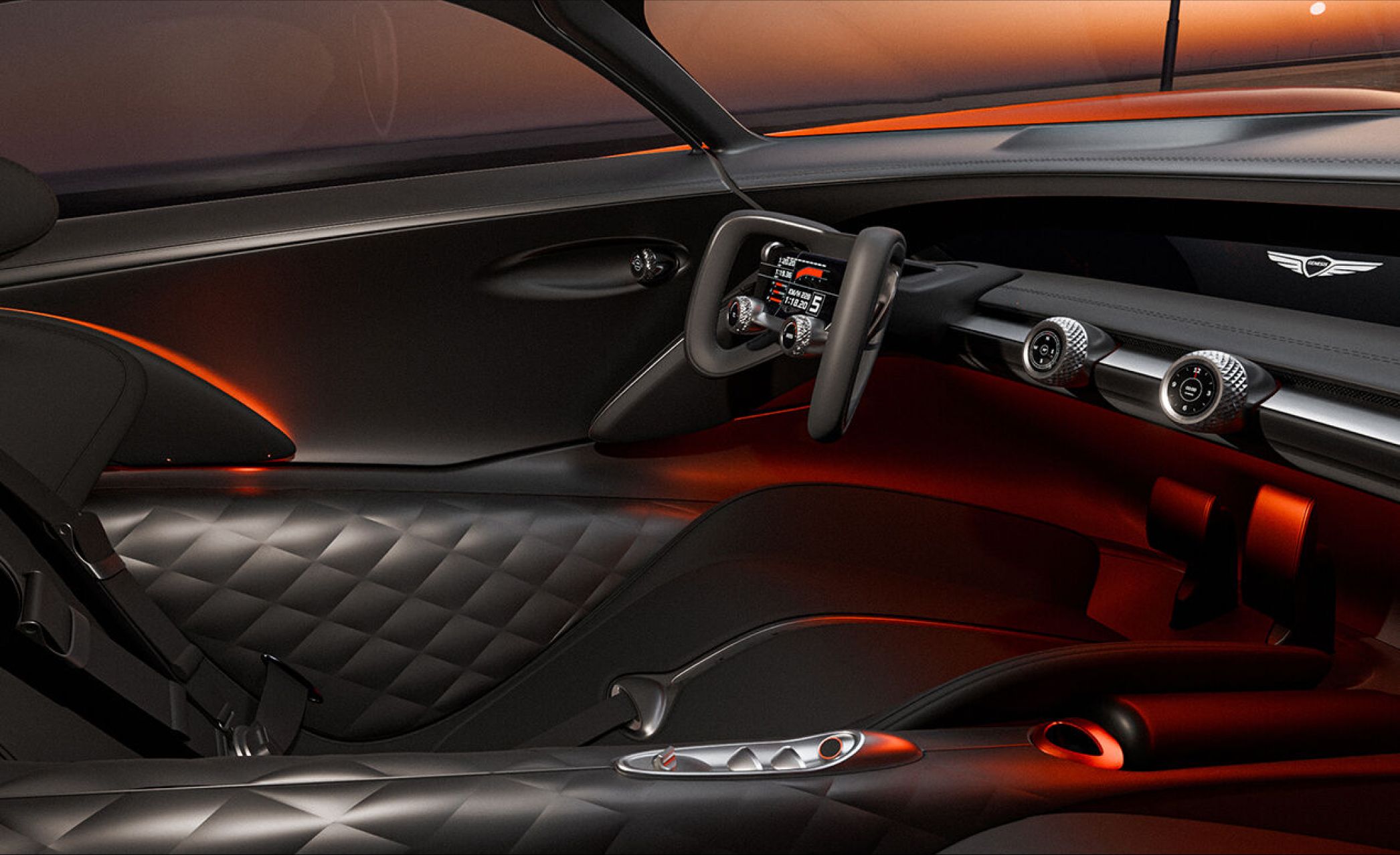 From the passenger seat, the view of the X Gran Berlinetta Concept’s driver’s seat is revealed. The interior is elegantly designed in black and silver, accented by a touch of fiery orange lighting. The steering wheel, featuring a central monitor and ribbon-like handles on either side, epitomizes modern sophistication.
