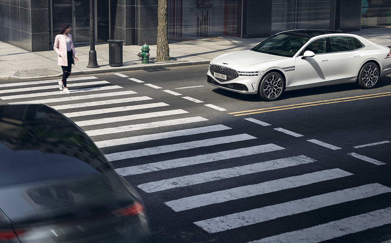 A pedestrian is crossing the crosswalk while Uyuni White G90 is stopped.