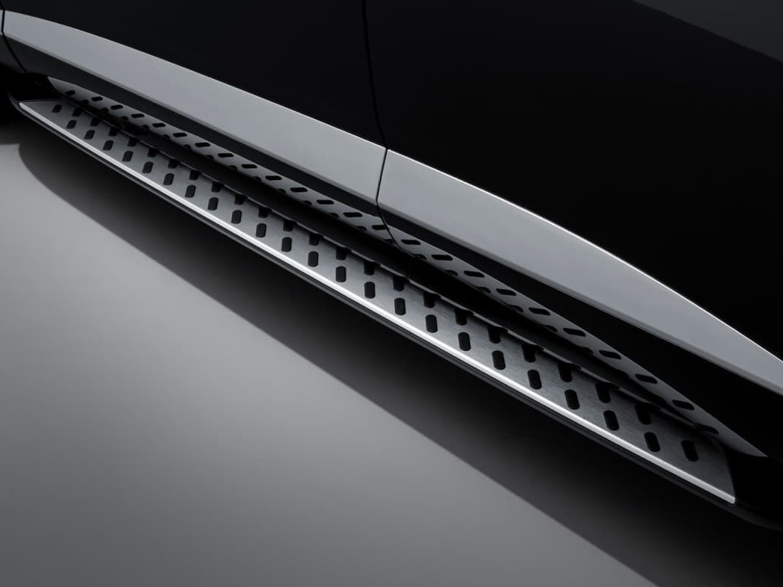 The metal side step with a diagonal pattern of black ovals is visible.