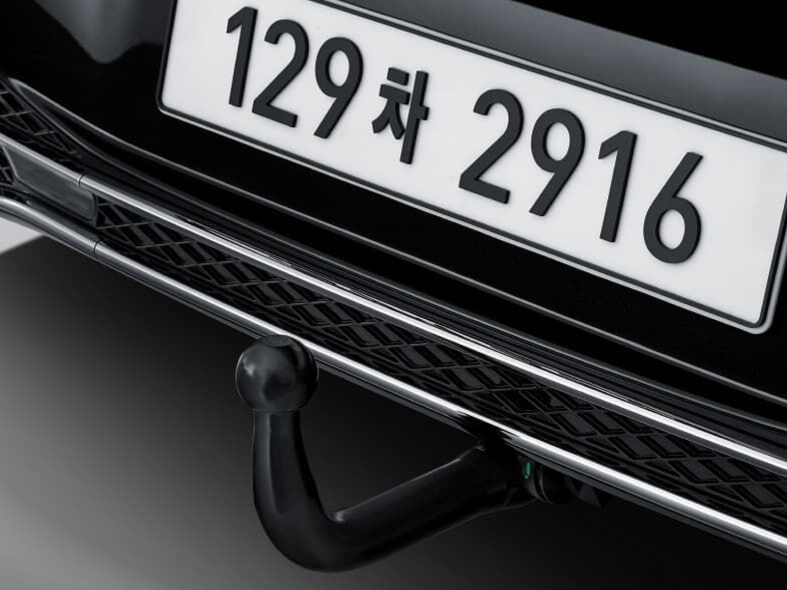 A trailer hitch is visible, mounted under the rear license plate of the Genesis vehicle.