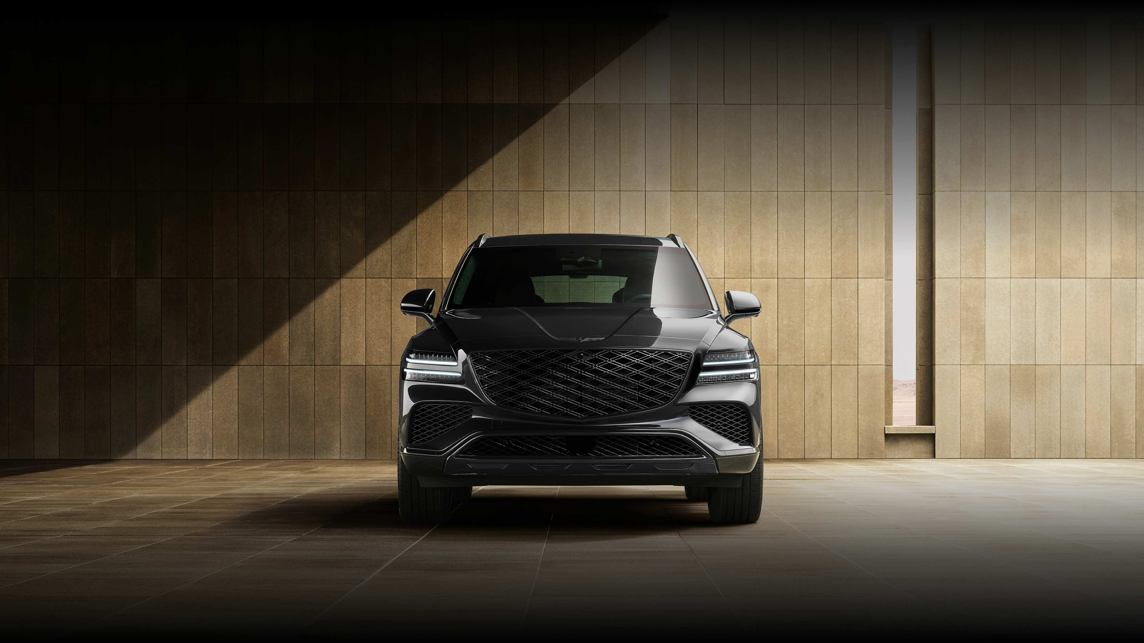 The front of the GV80 Black is visible, parked in front of a brown building with shadows cast diagonally across it.