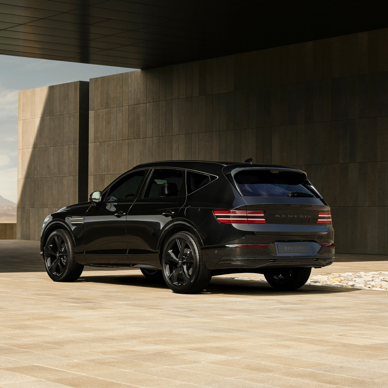 The rear of the GV80 Black is seen parked diagonally under the brown structure.