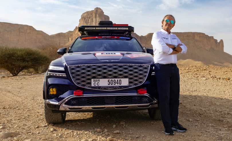 Next to the Genesis GV80 Desert Edition Concept, Jacky Ickx stands facing the front.