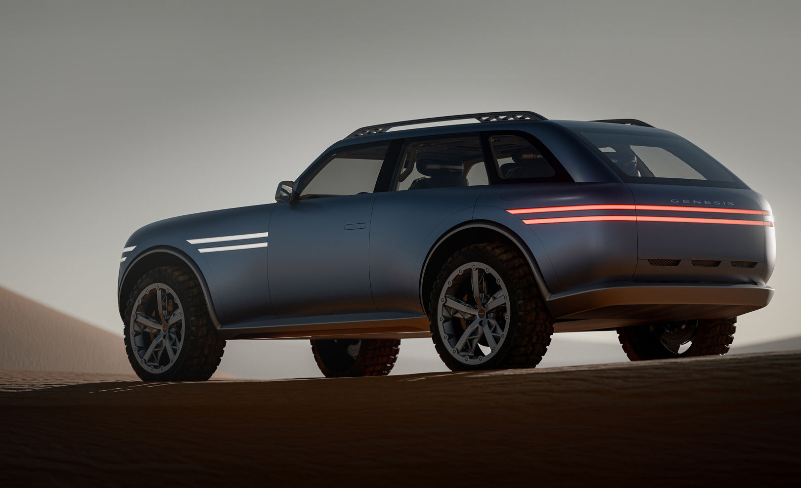 The Genesis X Gran Equator concept is parked in the middle of the desert, showing its side and rear. The two-line lamps at the front and rear are illuminated.
