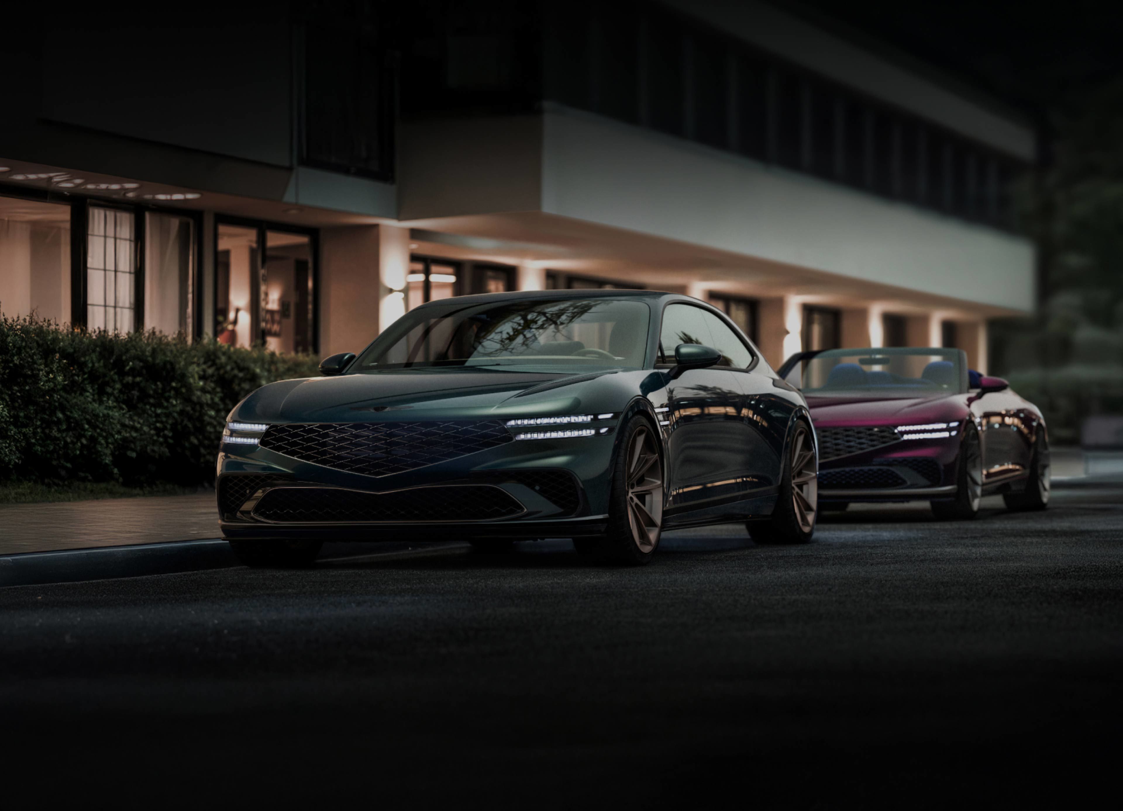 Genesis X Gran Coupe and Convertible concept vehicles are parked in front of a dark, luxurious background. At the front, the LED lights and signature grill stand out, and at the back, a convertible model with an open roof is visible.