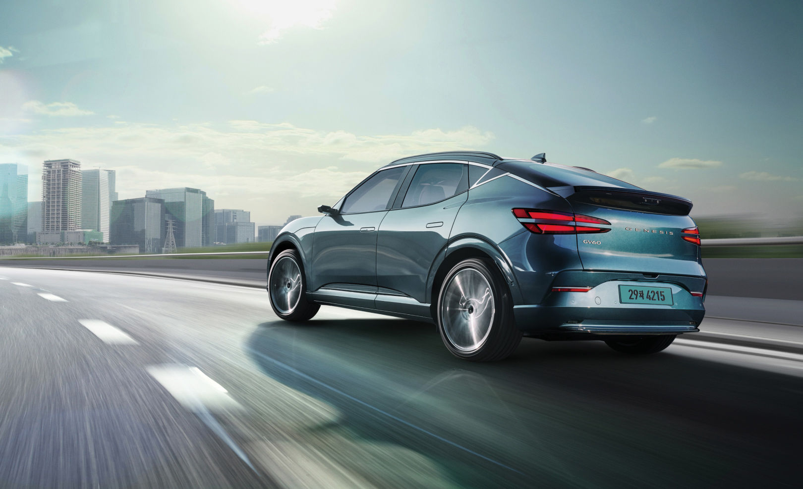  With a modern building in the background, you can see the rear of the GV60 driving fast on the highway.