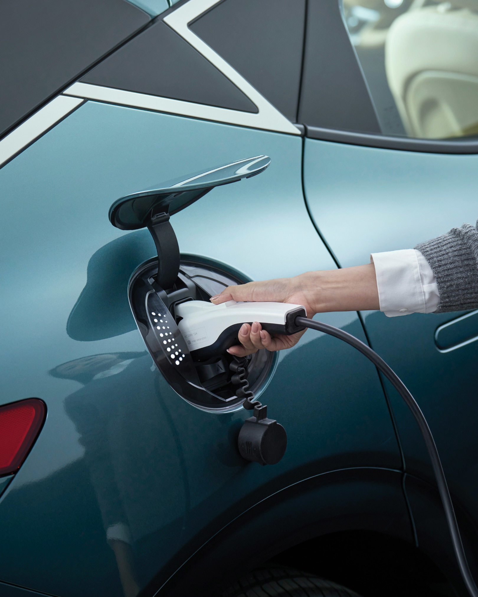 The Genesis car charger is open, and the hands of the person charging it appear to be enlarged.