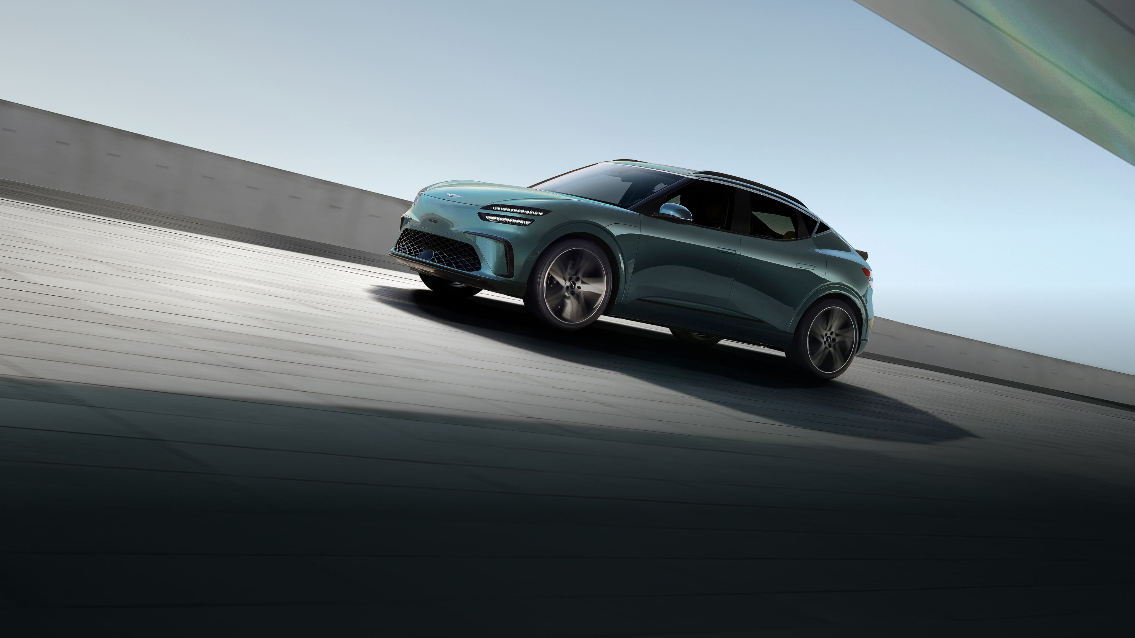 With the blue sky in the background, a Tromso green-colored GV60 is driving toward the side.
