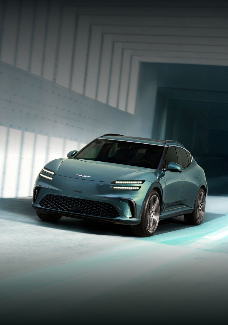 This is a Tromso green-colored GV60 dynamically driving on a blue-colored modern road.