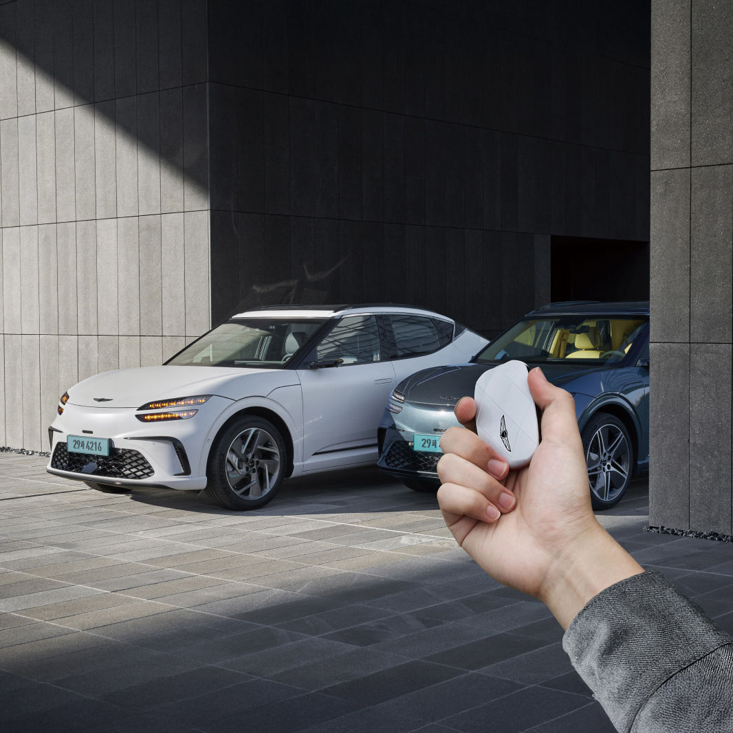 This shows the vehicle being remotely controlled from outside using the smart key. A person's hand is seen holding a white smart key.