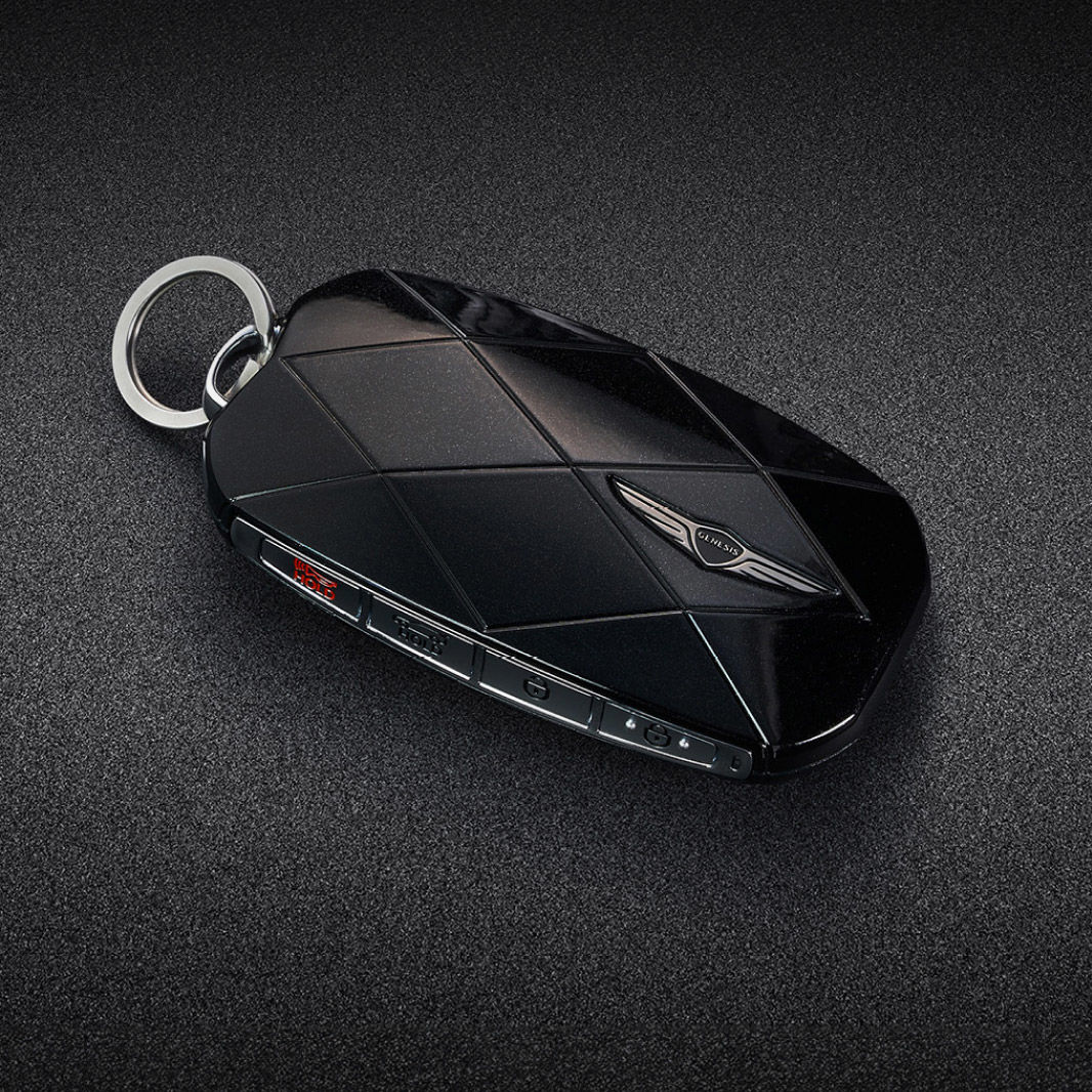 The black smart key is adorned with a Genesis emblem and diamond pattern lines.